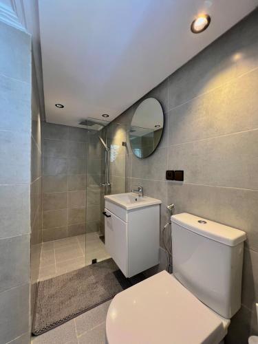 ein Badezimmer mit einer weißen Toilette und einem Spiegel in der Unterkunft C1, Chic Seaside Stay at Carrousel Mall, Walk Everywhere in Rabat