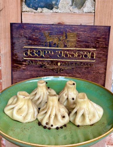 a green plate of dumplings in front of a box at Dzvel Ubanshi in Gori