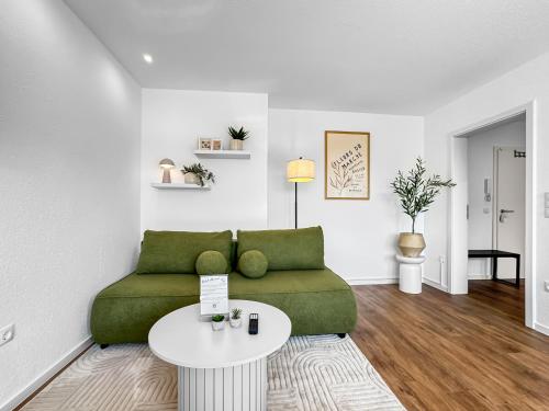 a living room with a green couch and a table at Modernes Apartment 'Ulla' in Diepholz in Diepholz
