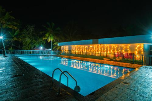 a swimming pool with lights on the side of a building at Munroe Island Lake Resort in Kollam