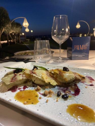 a plate of food on a table with wine glasses at Palmar Boutique Hotel in Campofelice di Roccella