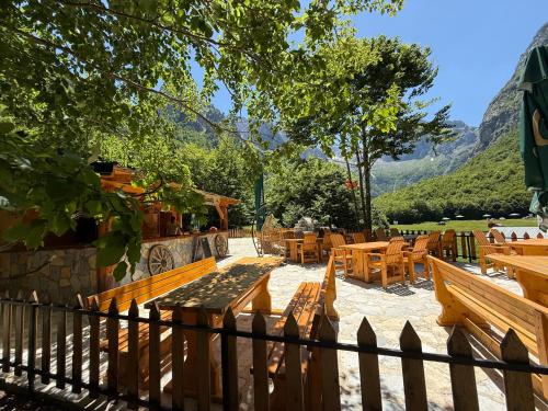 a patio with wooden benches and tables and mountains at WildBeauty Grebaje in Vusanje