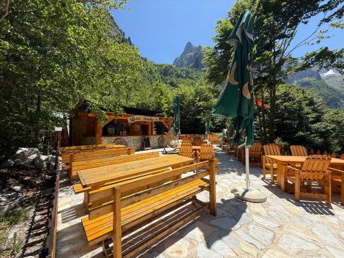 a group of wooden benches and an umbrella at WildBeauty Grebaje in Vusanje