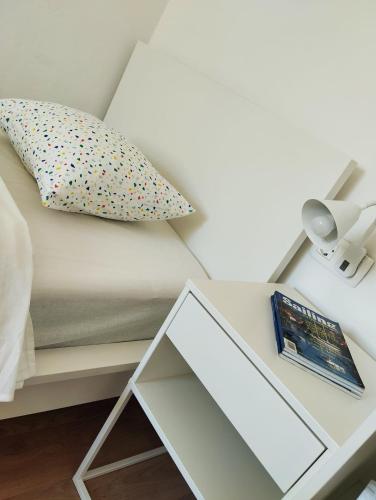 a white bed with a pillow and a glass table at Sobe Tramontana in Murter