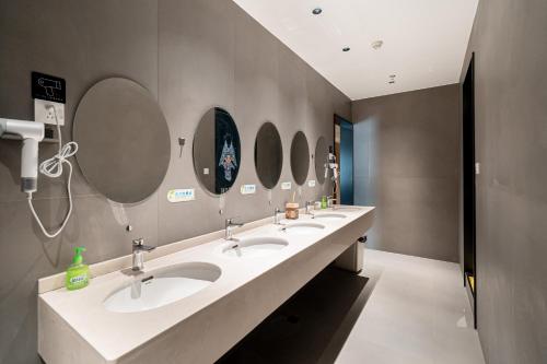a bathroom with three sinks and three mirrors at Dengba Inn - Shanghai Stadium Tianyaoqiao Road Branch in Shanghai