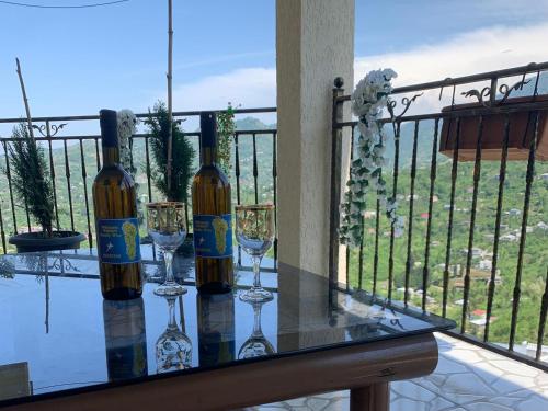 two bottles of wine on a glass table with wine glasses at tamazis guest house in Batumi