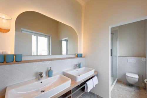 a bathroom with a sink and a mirror and a toilet at Appartementhaus Meeresburg in Norderney