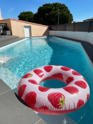 a swimming pool with a strawberry float in the middle at La Villa des Cistes au calme vue Étangs in Narbonne