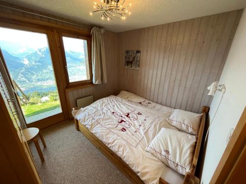 a small bedroom with a bed with a mountain view at Chalet Fava in Plan Fey
