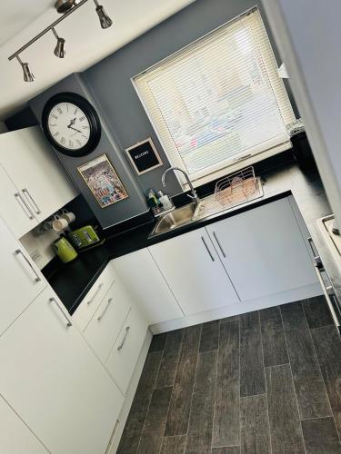 a kitchen with a sink and a clock on the wall at Stylish Marina Apartment with Stunning Views in Portishead