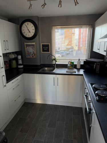 a kitchen with a sink and a clock on the wall at Stylish Marina Apartment with Stunning Views in Portishead