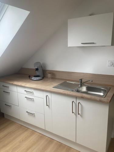 une cuisine avec des armoires blanches et un évier dans l'établissement Résidence des Hortensias, à Lorient