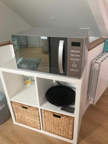 d'un four micro-ondes installé sur une étagère avec une table. dans l'établissement Résidence des Hortensias, à Lorient