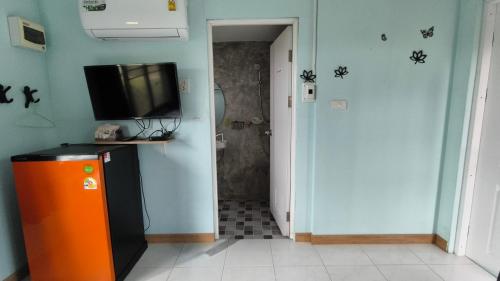 a room with a refrigerator and a television on a wall at โซพราว เขาค้อ So Proud Khaokho in Khao Kho