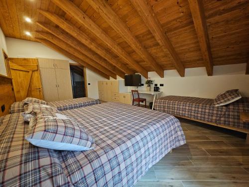 two beds in a room with wooden ceilings and a table at La Genzianella affittacamere in Santo Stefano dʼAveto
