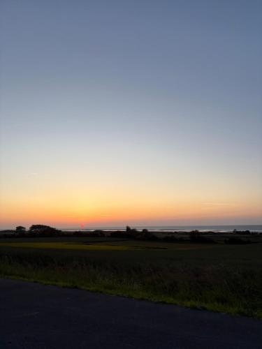un coucher de soleil sur un champ avec une route dans l'établissement appartement vue sur port de plaisance, à Courseulles-sur-Mer