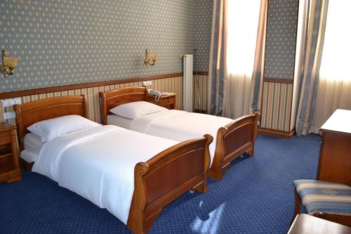 two beds in a room with blue carpet at Florence Hotel in Odesa