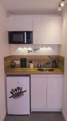 une petite cuisine avec un évier et un micro-ondes dans l'établissement Studio privé avec entrée indépendante, à Saint-Raphaël