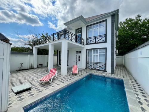a house with a swimming pool and two red chairs at White Terrace Villa in Gabala