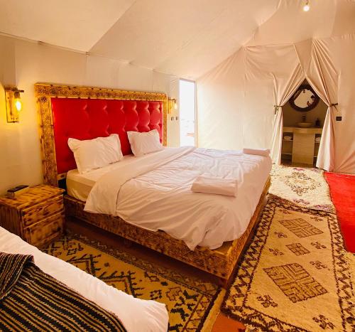 a bedroom with a large bed with a red headboard at Outdoor luxury camp in Merzouga