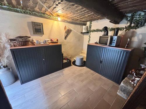 une cuisine avec deux armoires noires et un sol carrelé dans l'établissement Dépendance atypique avec jacuzzi inclus, à Mallemort