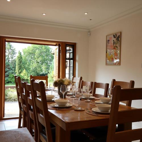 a dining room with a wooden table with wine glasses at Chimneys Hot Tub Country Escape in Stourbridge