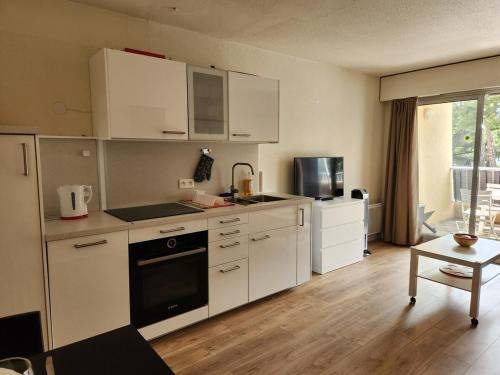 une cuisine avec des armoires blanches et un four à plaques de cuisson dans l'établissement Entre mer et palmiers, à Hyères