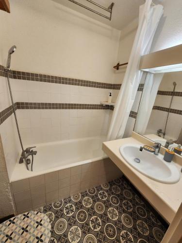 une salle de bain avec une baignoire, un lavabo et un miroir dans l'établissement Entre mer et palmiers, à Hyères