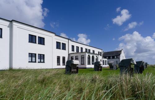 a white building with a grassy field in front of it at Appartementhaus Meeresburg in Norderney