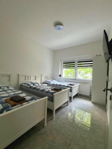 Un dormitorio con tres camas y una ventana. en Rhein Apart 1 near Cologne Messe, en Colonia