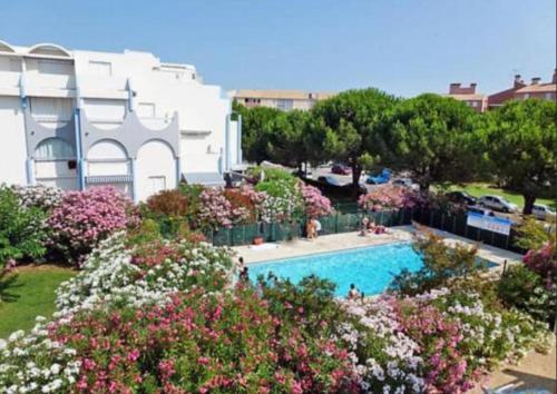 - une vue sur une piscine fleurie et un bâtiment dans l'établissement Studio Les Floralies 2 du Grau du Roi, au Grau-du-Roi