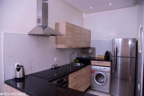 a kitchen with a stainless steel refrigerator and a dishwasher at VILLA CHEZ IMANE avec piscine chauffée a Orangeraie Dyar Shemsi in Riaïna