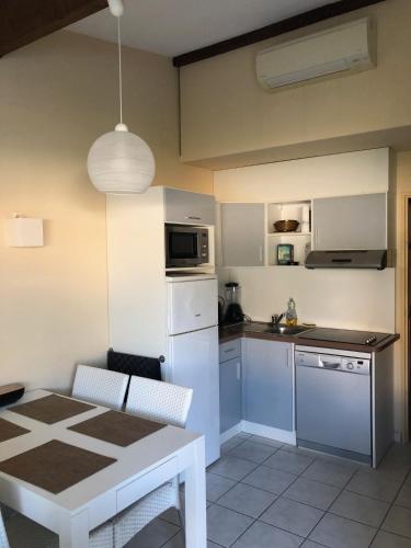 une cuisine avec un réfrigérateur blanc et une table dans l'établissement Maison saint cyprien plage, à Saint-Cyprien