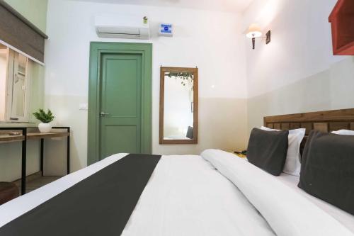 a bedroom with a large bed and a green door at Hotel O Pacific Mall Rajpur Road in Dehradun