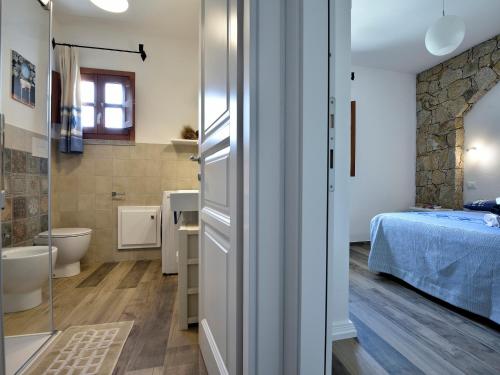 a bathroom with a toilet and a bed in a room at Villa Menhir in Lotzorai