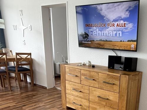 a living room with a dresser and a tv on a wall at Fehmarn Burgtiefe Südstrand 2 Zimmer Wohnung SEESTERN mit Süd-Bk WaMa in Fehmarn