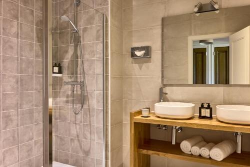 a bathroom with two sinks and a shower at Maison Zugno Hôtel & Spa in Barretaine
