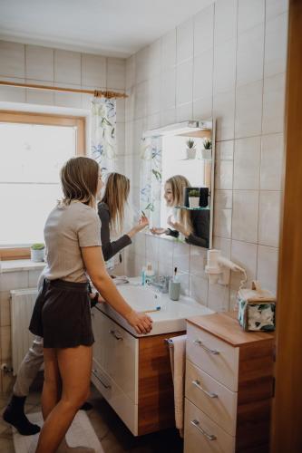 a woman standing in front of a bathroom mirror at Dorfcafe Unken Hotelpension sWirtshaus im Dorf in Unken