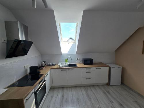 a kitchen with white cabinets and a window at Apartmán pod Javorovým vrchem in Nebory