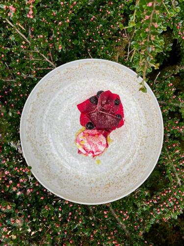 a white plate with a red flower on it at Maison Zugno Hôtel & Spa in Barretaine