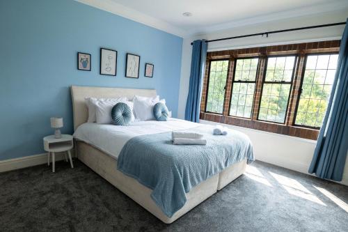 a blue bedroom with a bed and a window at Chimneys Hot Tub Country Escape in Stourbridge