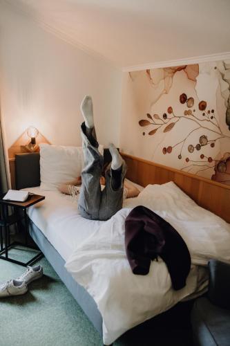 a bedroom with a bed with a persons feet up on it at Dorfcafe Unken Hotelpension sWirtshaus im Dorf in Unken