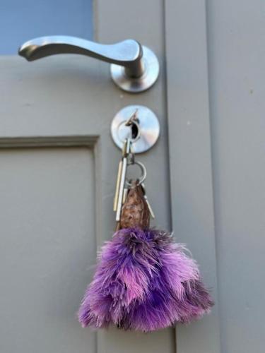 a purple furry keychain hanging from a door handle at Serendipity Guest Cottage in Prince Albert