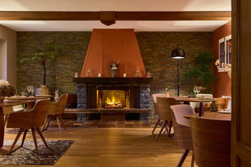 a fireplace in a restaurant with tables and chairs at Maison Zugno Hôtel & Spa in Barretaine