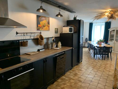 une cuisine avec des appareils noirs et une salle à manger dans l'établissement Maison au coeur du village de la Salvetat sur Agout, à La Salvetat-sur-Agout