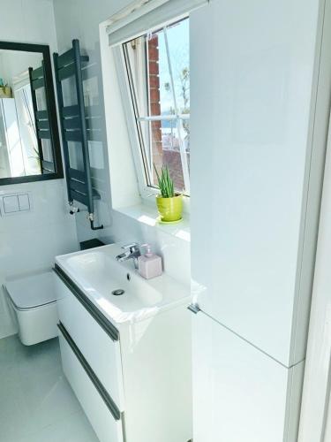 a white bathroom with a sink and a window at Marina Mikołajki in Mikołajki