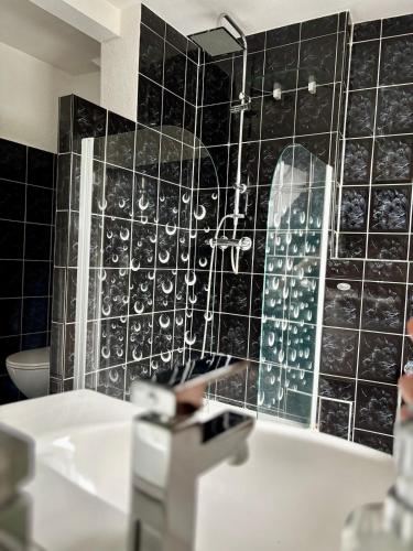 a bathroom with a black tiled wall and a tub at Ferienidyll an der Recknitz in Tessin