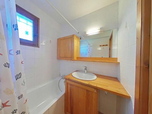 une salle de bain avec un lavabo, une baignoire et un miroir dans l'établissement Appt T3 au centre, terrasse sud, proche commerces - FR-1-241-169, au Grand-Bornand