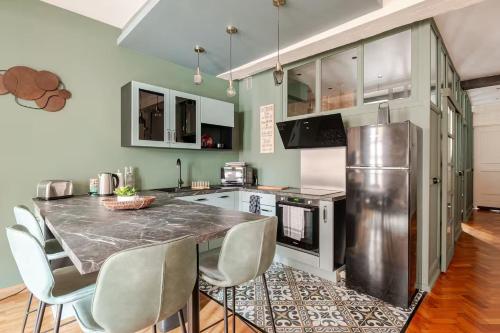 une cuisine avec une table avec des chaises et un réfrigérateur dans l'établissement OWL PRESTIGE Dijon, à Dijon