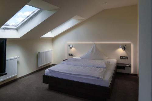 a bedroom with a large white bed and a window at Hotel am Berg Esslingen in Esslingen